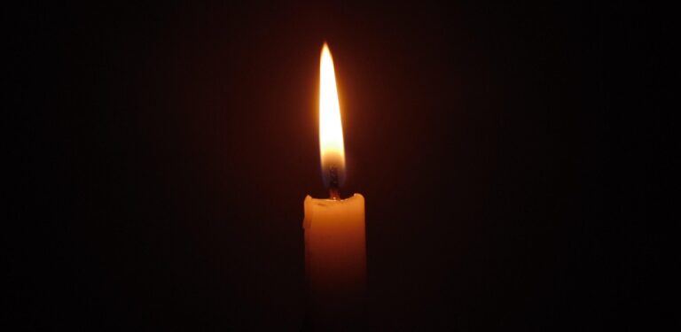 Single burning candle in darkness