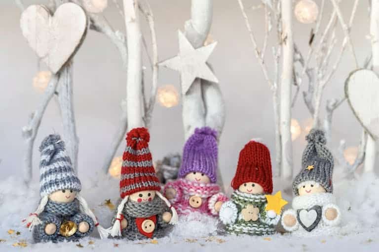Charming knitted dolls in winter hats amidst a festive snowy backdrop, perfect for holiday decorations.