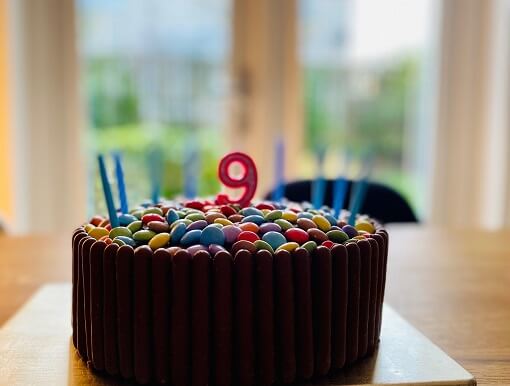 Chocolate birthday cake with candles, decorated with chocolate fingers and smarties