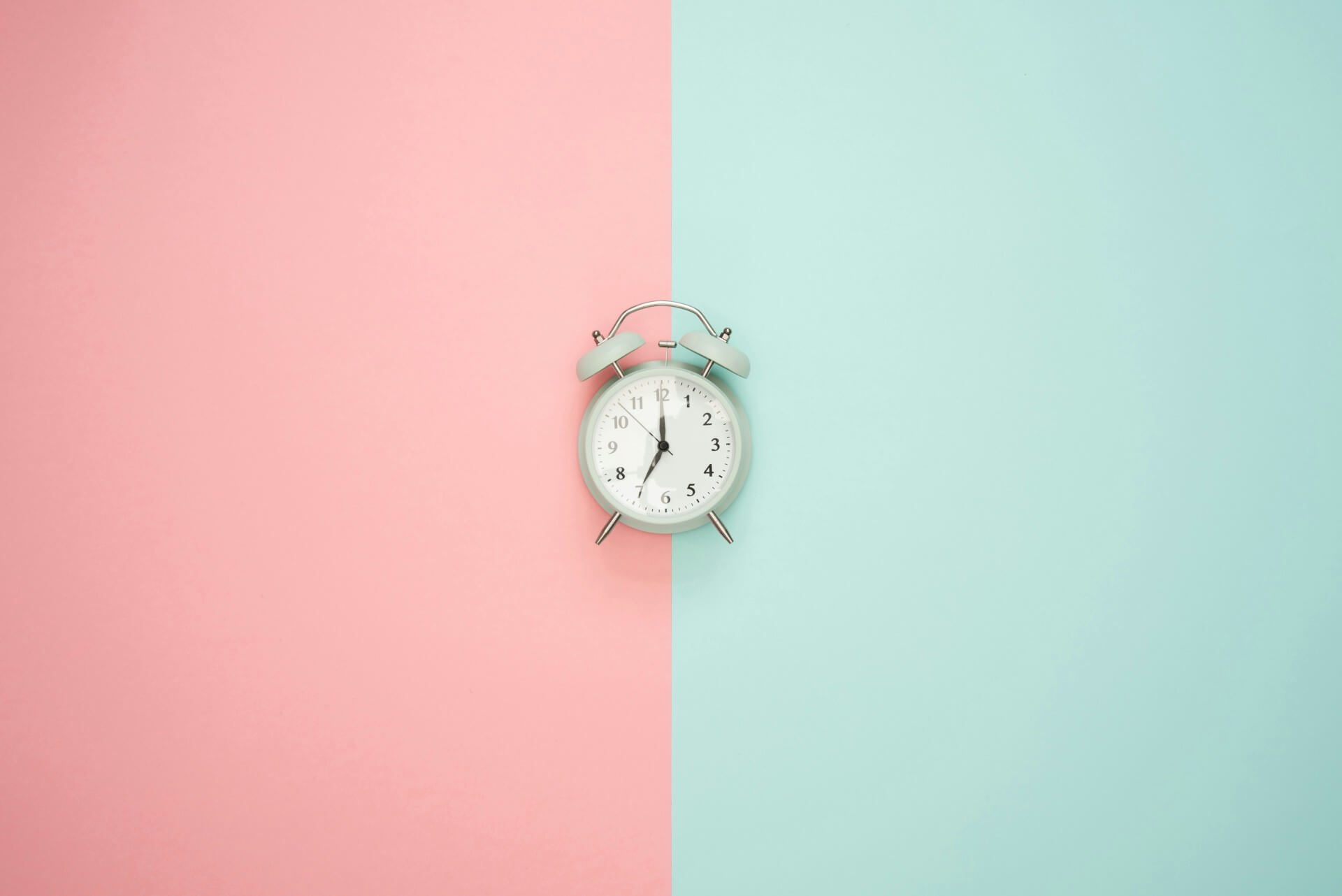 Alarm clock on pink and blue background. Ideas for how to create a weekend morning routine