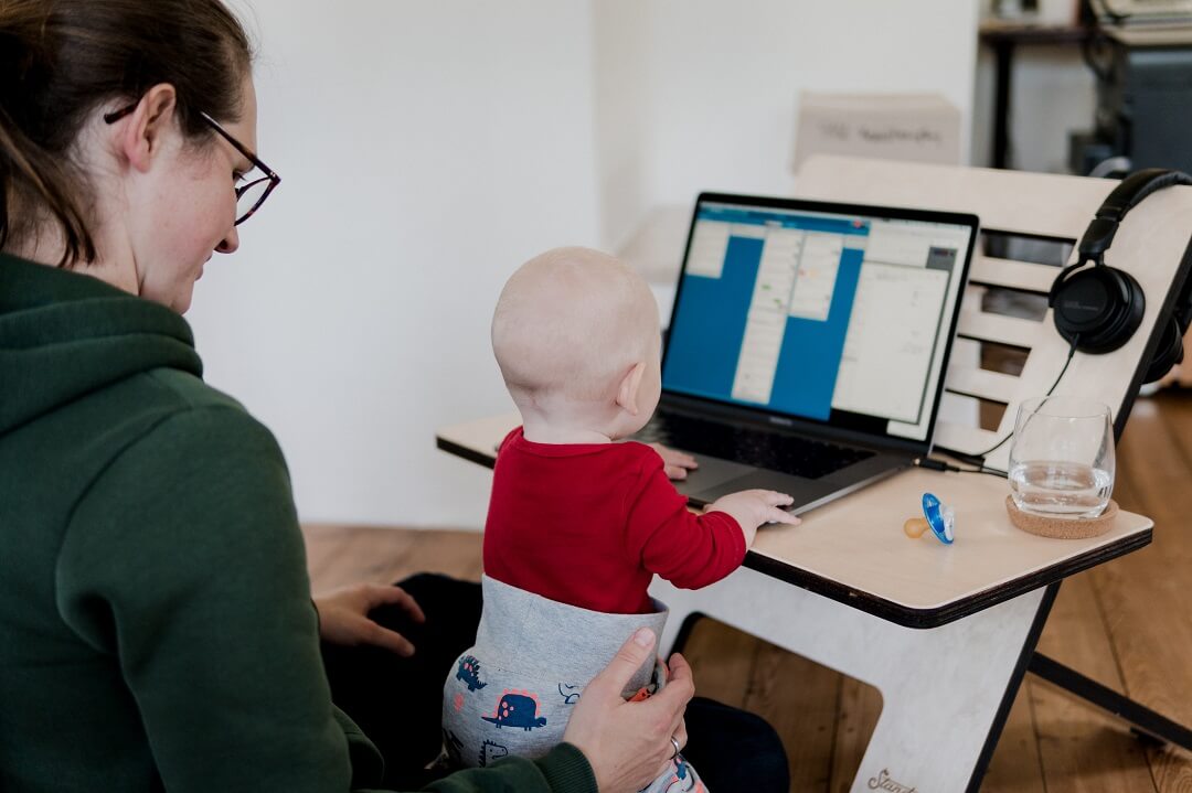 Mother working at laptop with baby on her knee