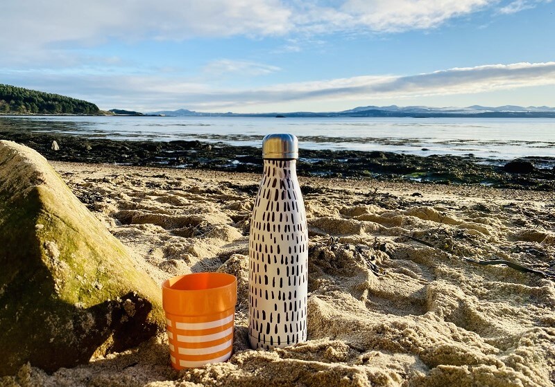 Flask in the sand on a beach