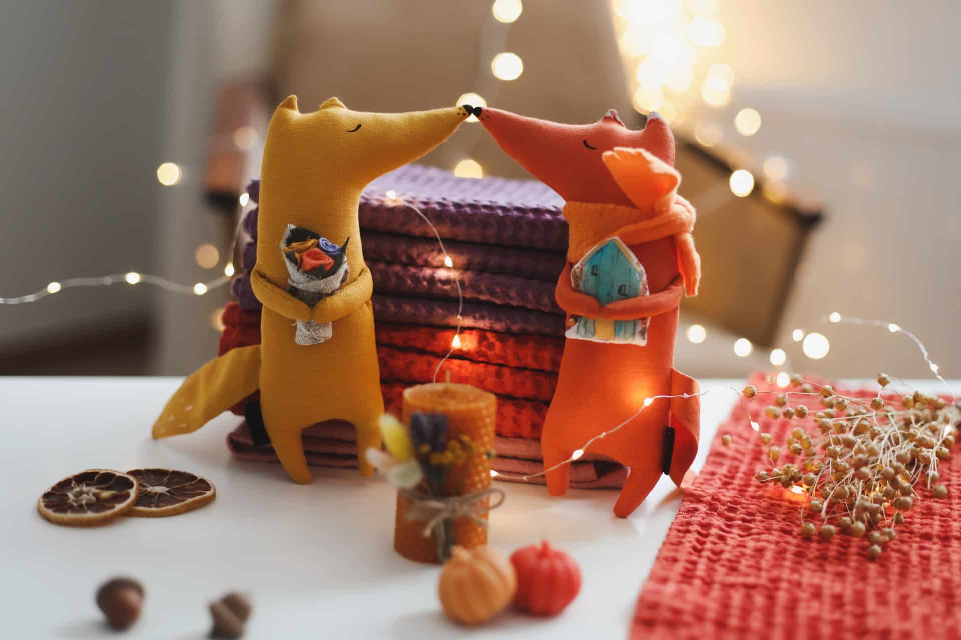 Two fox toys in cosy setting, with fairy lights. Blog post image for The connection between hygge and mental wellbeing.